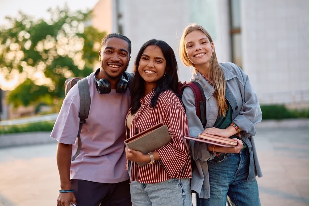 Trois étudiants souriants sur le campus